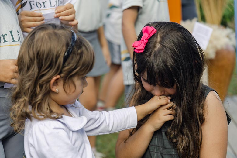 Menina beijando a mão de uma amiguinha em escola cristã bilíngue