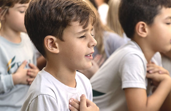 Crianças de olhos fechados fazendo oração em escola cristã bilíngue
